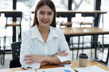 İşyerinde bilgisayarları ve finansal bütçe belgelerini kullanarak başarılı bir şekilde yatırım yaptığı için gülümseyen bir kadın işadamının portresi..