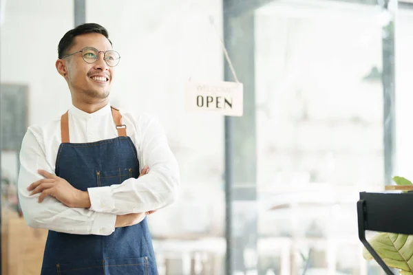 Portrait of a beautiful Asian man running a small business showing a smiling face, a coffee shop owner opening a shop to welcome customers in the new morning, SME concepts.
