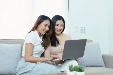 Igbtq, Igbt konsepti, homoseksüellik, iki Asyalı kadının birlikte mutlu poz verip birbirlerini severken koltukta bilgisayar bilgisayarı oynaması..