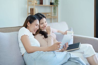 Igbtq, Igbt konsepti, homoseksüellik, iki Asyalı kadının birlikte mutlu poz vermeleri ve kanepede tablet oynarken birbirlerini sevmeleri..