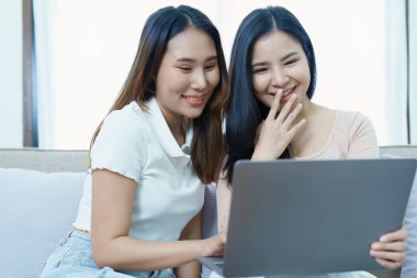 Igbtq, Igbt konsepti, homoseksüellik, iki Asyalı kadının birlikte mutlu poz verip birbirlerini severken koltukta bilgisayar bilgisayarı oynaması..