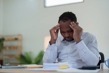 Stresli Amerikalı Yanmış Afrikalı iş adamı evrak işleriyle uğraşıyor. Migren saldırısı, serbest çalışma, evden çalışma..