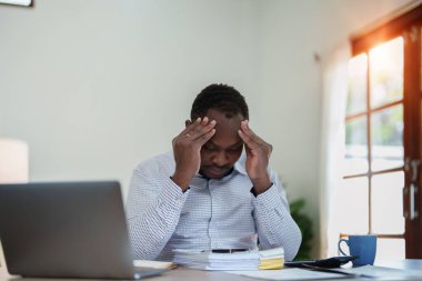 Stresli Amerikalı Yanmış Afrikalı iş adamı evrak işleriyle uğraşıyor. Migren saldırısı, serbest çalışma, evden çalışma..