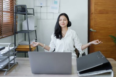 Genç Asyalı kadın portresi işten önce yoga duruşunda meditasyon yapıyor..