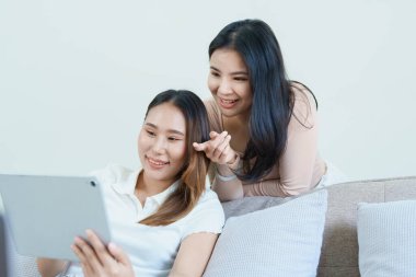 Igbtq, Igbt konsepti, homoseksüellik, iki Asyalı kadının birlikte mutlu poz vermeleri ve kanepede tablet oynarken birbirlerini sevmeleri..