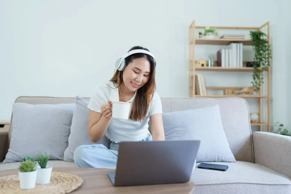 亚洲少女使用电脑 在沙发上戴耳机 — 图库照片
