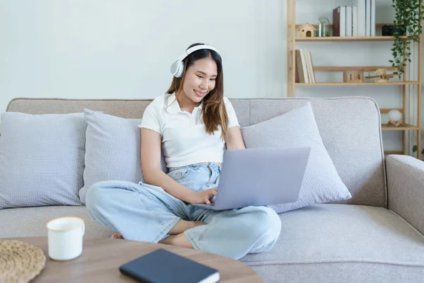 亚洲少女使用电脑 在沙发上戴耳机 — 图库照片