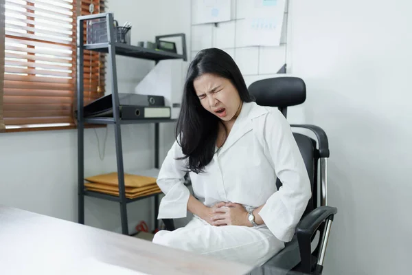 stock image Portrait of a young Asian female representative showing acute abdominal pain from sitting for a long time at work. High quality photo