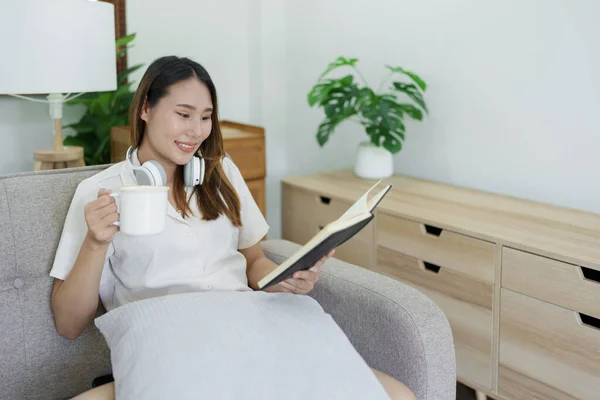 Mujer Asiática Leyendo Libro Usando Auriculares Beber Taza Café Relajante —  Fotos de Stock