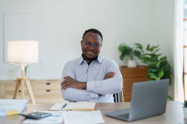 Orta yaşlı Amerikalı Afrikalı iş adamı bilgisayarlı dizüstü bilgisayarı elinde tutuyor ve kazanan elini kaldırıyor. Başarı başarısını kutlamaktan mutluluk duyuyoruz..