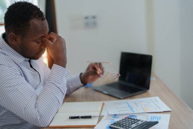 Stresli Amerikalı Yanmış Afrikalı iş adamı evrak işleriyle uğraşıyor. Migren saldırısı, serbest çalışma, evden çalışma..