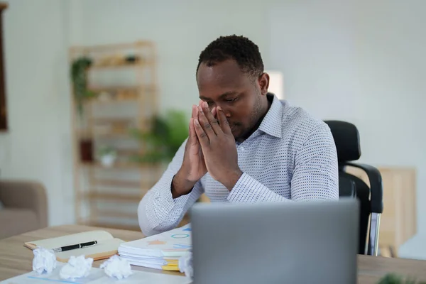 Burnout American African business man in stress works with many paperwork document, migraine attack, Freelance, work from home.