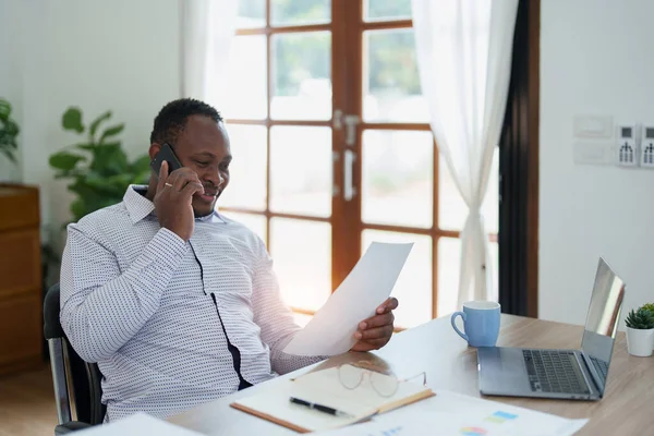 stock image middle aged man American African using smart phone mobile and laptop computer with planning working on financial document, tax, exchange, accounting and Financial advisor.