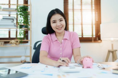 Yatırım planı, genç Asyalı kadın kavanozda para saklıyor ve tasarruf hesaplamak için hesap makinesi kullanıyor..