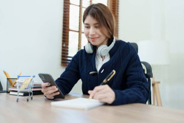 Çevrimiçi Alışveriş ve İnternet Ödemeleri, Asyalı adam internet üzerinden alışveriş yapmak veya dijital dünyada ayak işleri yapmak için kredi kartı ve cep telefonlarını kullanıyor