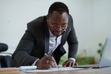 Orta yaşlı Amerikalı Afrikalı adam bilgisayarını kullanarak finansal belge, vergi, döviz, muhasebe ve mali danışman üzerinde çalışıyor. denetleyici veya denetim kavramları.