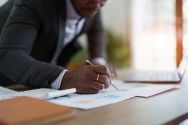 Orta yaşlı Amerikalı Afrikalı adam bilgisayarını kullanarak finansal belge, vergi, döviz, muhasebe ve mali danışman üzerinde çalışıyor. denetleyici veya denetim kavramları.