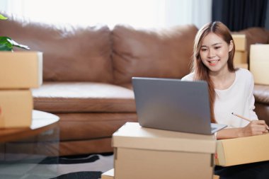 Bağımsız Asyalı kadın çevrimiçi satıcının müşterilere ve KOBİ dağıtım konseptine göndermek üzere ürünlerini paketleyen küçük işletme girişimcisi başlatılıyor.