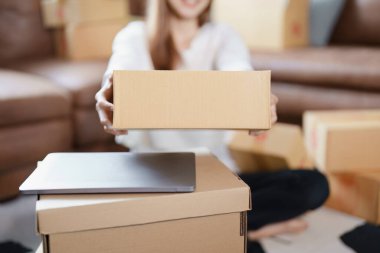 Bağımsız Asyalı kadın çevrimiçi satıcının müşterilere ve KOBİ dağıtım konseptine göndermek üzere ürünlerini paketleyen küçük işletme girişimcisi başlatılıyor.