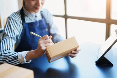 Bağımsız Asyalı kadın çevrimiçi satıcının müşterilere ve KOBİ dağıtım konseptine göndermek üzere ürünlerini paketleyen küçük işletme girişimcisi başlatılıyor.