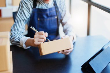 Bağımsız Asyalı kadın çevrimiçi satıcının müşterilere ve KOBİ dağıtım konseptine göndermek üzere ürünlerini paketleyen küçük işletme girişimcisi başlatılıyor.