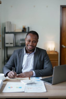 Orta yaşlı Amerikalı Afrikalı adam bilgisayarını kullanarak finansal belge, vergi, döviz, muhasebe ve mali danışman üzerinde çalışıyor. denetleyici veya denetim kavramları.