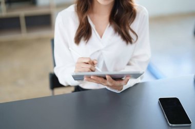 İş yeri sahibi ya da Asyalı kadın pazarlamacılar ofis çalışmalarında tablet bilgisayar kullanıyorlar.