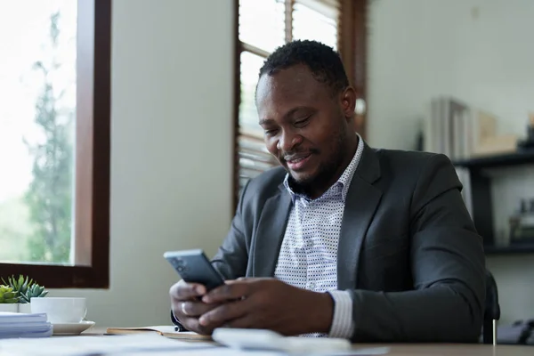 中年男性財務文書 会計および財務顧問に取り組む計画とスマートフォンの携帯電話とラップトップコンピュータを使用してアフリカ系アメリカ人 — ストック写真