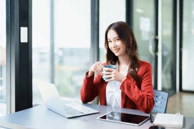 Bilgisayarda konuşan ve kahve içen bir iş kadını portresi..