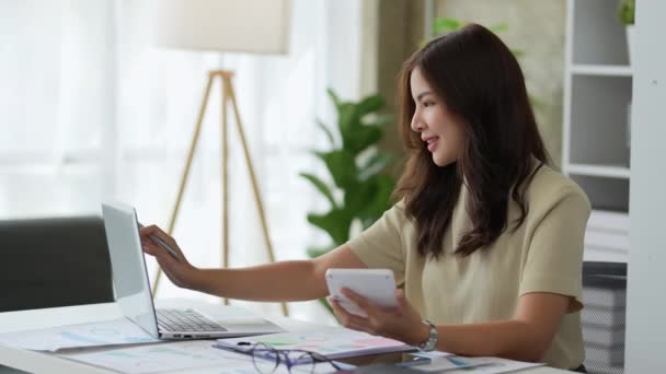 アジアの若い女性実業家は 計算機やコンピュータを使用して マーケティング計画の予算作成に取り組んでいます 高品質4K映像 — ストック動画