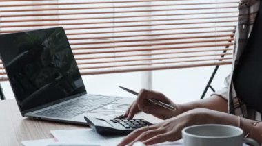 Genç Asyalı kadın evdeki masada hesap makinesiyle mali beyan belgelerini kontrol ediyor. Yüksek kalite 4k görüntü