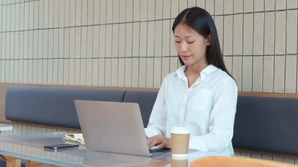 Молодая Азиатка Работает Компьютером Держит Ручку Делать Заметки Блокноте Кафе — стоковое видео