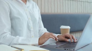 Bilgisayarda çalışan genç Asyalı bir kadın ve elinde bir kafedeki not defterine not almak için kalem tutuyor. Yüksek kalite 4k görüntü