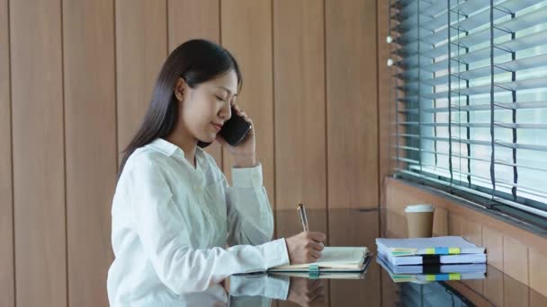 Young Asian Woman Using Smartphone Mobile Talking Business Take Notes — Stock Video