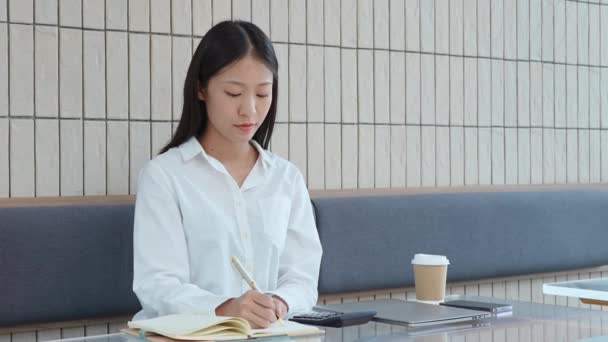 Молодая Азиатка Работает Калькулятором Расчета Держит Ручку Делать Заметки Блокноте — стоковое видео
