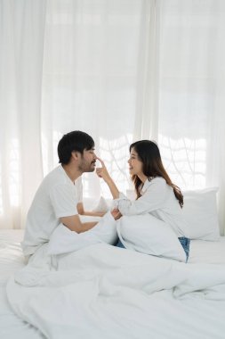 Yatakta yatan Asyalı romantik çift, şehvetli ön sevişmelerden zevk alıyor. Yatakta birlikte yatan genç ve şehvetli bir çift. Güzel bir çift yatakta öpüşüyor.