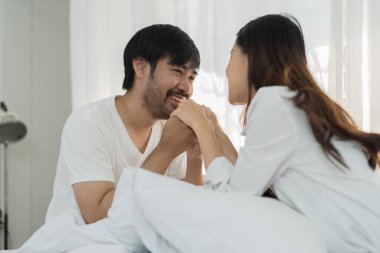 Yatakta yatan Asyalı romantik çift, şehvetli ön sevişmelerden zevk alıyor. Yatakta birlikte yatan genç ve şehvetli bir çift. Güzel bir çift yatakta öpüşüyor.