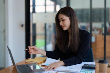 Güzel Asyalı genç iş kadını bilgisayar dizüstü bilgisayarında buluşup mali belge, vergi, döviz, muhasebe ve mali danışman üzerinde çalışıyor. Yüksek kalite fotoğraf