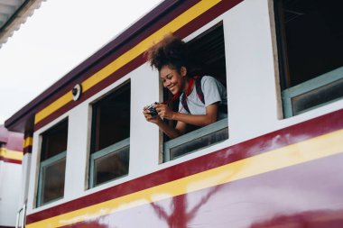 Afro-Amerikan turistler tren istasyonunda yolculuklarını beklerken mutlu yüz ifadeleri sergiliyorlar.