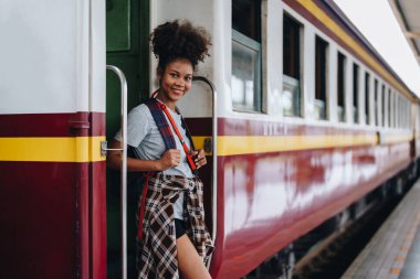 Afro-Amerikan turistler tren istasyonunda yolculuklarını beklerken mutlu yüz ifadeleri sergiliyorlar.