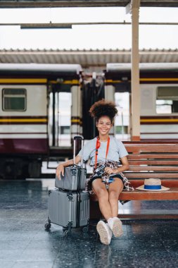 Afro-Amerikan turistler tren istasyonunda yolculuklarını beklerken mutlu yüz ifadeleri sergiliyorlar.