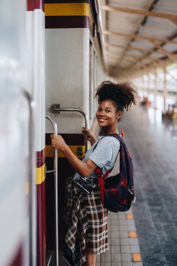 Afro-Amerikan turistler tren istasyonunda yolculuklarını beklerken mutlu yüz ifadeleri sergiliyorlar.