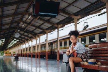 Afro-Amerikan turistler tren istasyonunda yolculuklarını beklerken mutlu yüz ifadeleri sergiliyorlar.