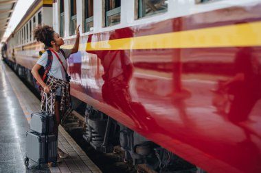 Afro-Amerikan turistler tren istasyonunda yolculuklarını beklerken mutlu yüz ifadeleri sergiliyorlar.