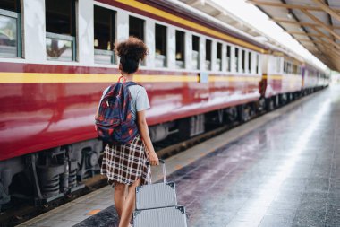 Afro-Amerikan turistler tren istasyonunda yolculuklarını beklerken mutlu yüz ifadeleri sergiliyorlar.