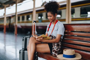 Afro-Amerikan turistler tren istasyonunda yolculuklarını beklerken mutlu yüz ifadeleri sergiliyorlar.