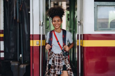 Afro-Amerikan turistler tren istasyonunda yolculuklarını beklerken mutlu yüz ifadeleri sergiliyorlar.