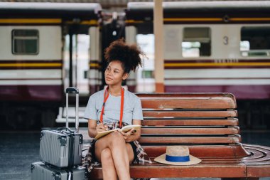 Afro-Amerikan turistler tren istasyonunda yolculuklarını beklerken mutlu yüz ifadeleri sergiliyorlar.