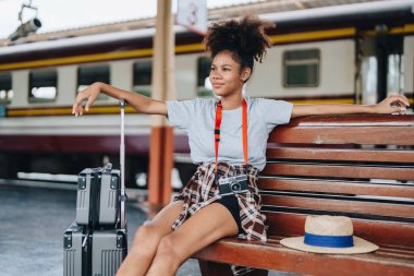 Afro-Amerikan turistler tren istasyonunda yolculuklarını beklerken mutlu yüz ifadeleri sergiliyorlar.