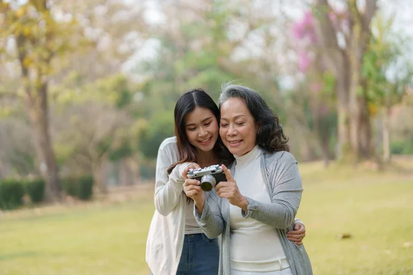 아시아의 어머니와 추억을 포착하기 카메라를 가지고 공원을 — 스톡 사진